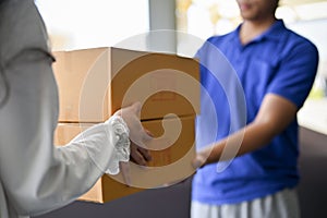 A woman receiving cardboard parcel boxes from a delivery man in front of the house's door