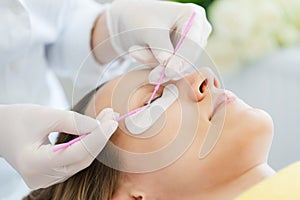 Woman receiving eyelash extension in salon