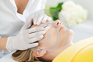 Woman receiving eyelash extension in salon
