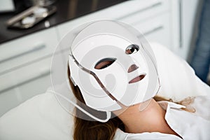 Woman receiving face light therapy in LED mask