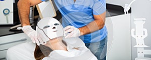 Woman receiving face light therapy in LED mask