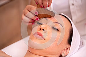 Woman receiving a facial madero massage with wooden massager