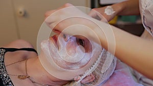 Woman receiving facial massage at beauty salon. Woman getting a cosmetic treatment, close-up. Beautician hands at work