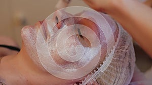 Woman receiving facial massage at beauty salon. Woman getting a cosmetic treatment, close-up. Beautician hands at work