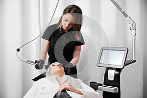 Woman receiving facial treatment in cosmetology clinic.
