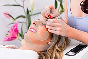 Woman receiving false eye lashes - beauty studio