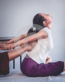 Woman receiving feet push on her back for Thai massage stretching in a Thai traditional spa