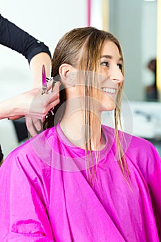 Woman receiving haircut from hair stylist or hairdresser