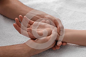 Woman receiving hand massage on soft towel, closeup