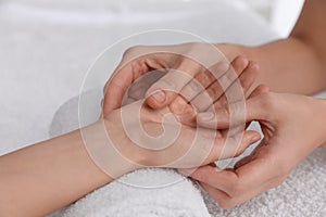 Woman receiving hand massage on soft towel, closeup
