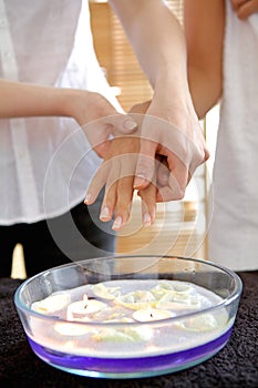 Woman receiving heat therapy on hand over bowl filled with candles