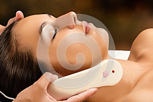 Woman receiving high frequency facial treatment.