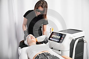 Woman receiving laser skincare treatment in cosmetology clinic.