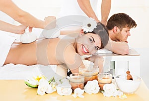 Woman receiving massage with herbal compress stamps photo