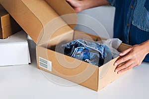 A woman receiving and opening a postal parcel box of clothing at home for delivery and online shopping concept