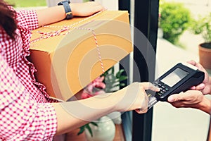 Woman receiving parcel from delivery man at the door and payment by credit card