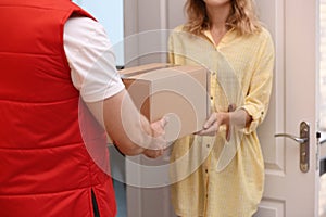 Woman receiving parcel from deliveryman indoors, closeup.