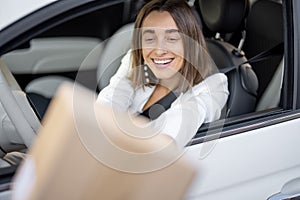 Woman receiving a parcel through the vehicle window on the go