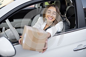 Woman receiving a parcel through the vehicle window on the go
