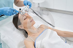 Woman receiving radiofrequency facial treatment in clinic