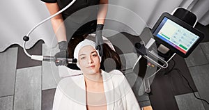 Woman receiving radiofrequency facial treatment in cosmetology clinic.