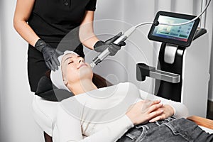 Woman receiving radiofrequency facial treatment in modern clinic.