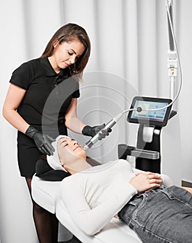 Woman receiving radiofrequency treatment in beauty clinic.