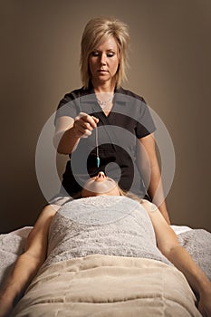 Woman receiving Reiki energy pendulum treatment at a spa