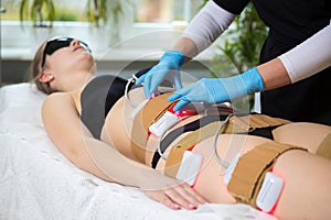 Woman receiving slimming lipo laser therapy in spa photo