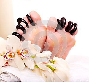 Woman receiving stone massage on feet.