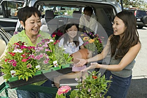 Woman Receiving Tray Of Flowers From Mother