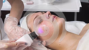 Woman receiving ultrasound cavitation facial peeling. Ultrasonic procedure.