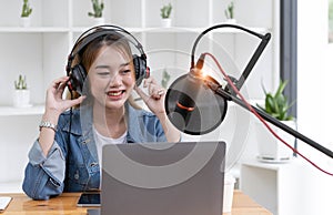 Woman recording a podcast on her laptop computer with headphones and a microscope. Female podcaster making audio podcast from her