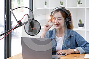 Woman recording a podcast on her laptop computer with headphones and a microscope. Female podcaster making audio podcast from her