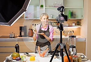 Woman recording video in her home kitchen, creating content for video blog