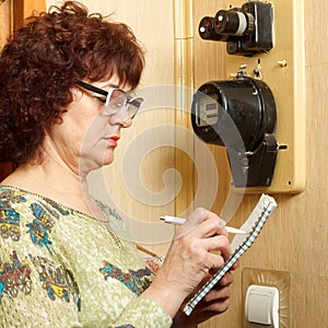 A woman records the testimony of an apartment electricity meter