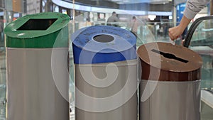 Woman recycles paper into the trash can with paper, plastic and glass sign. Waste sorting and recycling. Slow motion