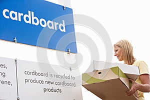 Woman At Recycling Centre Disposing Of Cardboard