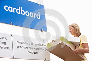 Woman At Recycling Centre Disposing Of Cardboard