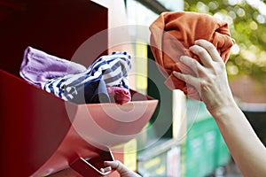 Woman Recycling Clothes At Clothing Bank