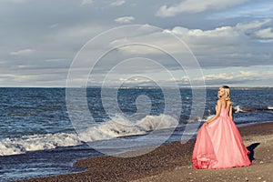 Woman in red ball gown at the beach
