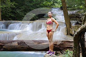 Woman with red bikini enjoy at Erawan Waterfall and natural