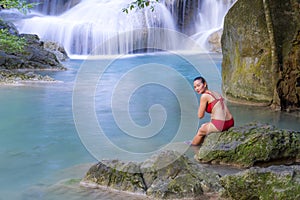 Woman with red bikini enjoy water at Erawan Waterfall and natural