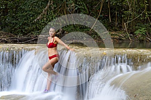 Woman with red bikini relax at Erawan Waterfall and natural