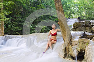 Woman in red bikini sexy at Erawan Waterfall and natural