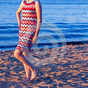 A woman in a red and blue knitted dress with a Missoni zigzag pattern on the beach in summer