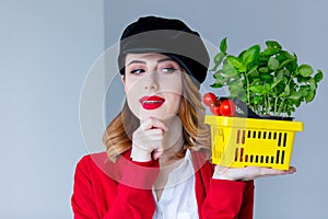 Woman in red cardigan and hat with herbs and tomatoes in yellow