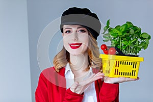 Woman in red cardigan and hat with herbs and tomatoes in yellow