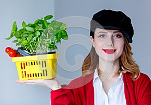 Woman in red cardigan and hat with herbs and tomatoes in yellow