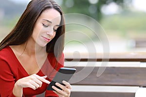 Woman in red checking smart phone on a bench